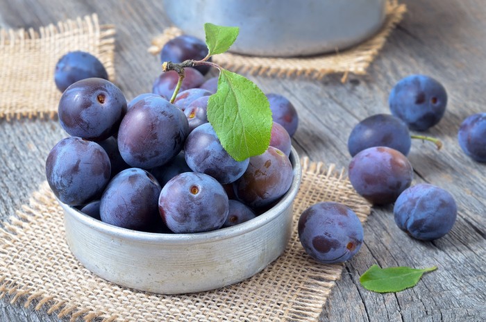 Plums in bowl on the wooden table